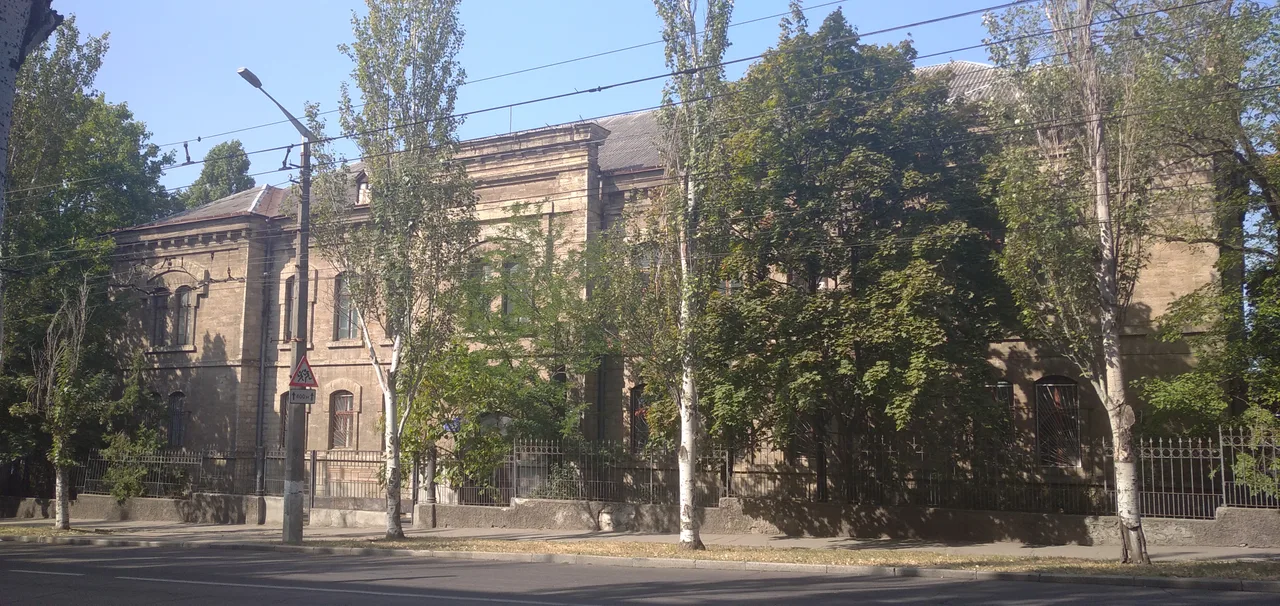 Широкий зелений вигляд історичної будівлі залізничного училища, яку використовує Миколаївський фаховий коледж транспортної інфраструктури.