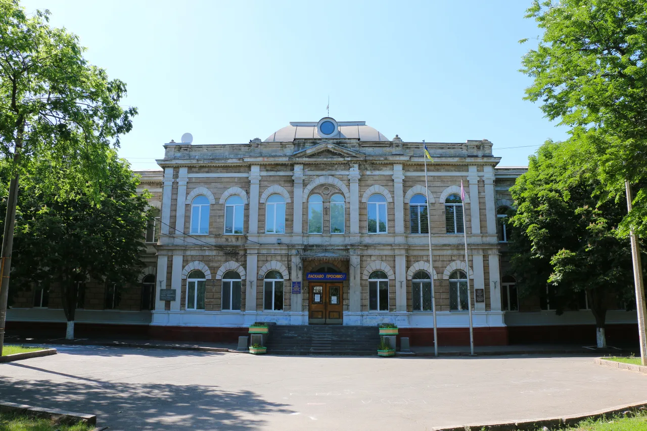 Архівний фронтальний вигляд будівлі Маріїнської гімназії у Миколаєві з арковими вікнами, пілястрами й центральним фронтоном.