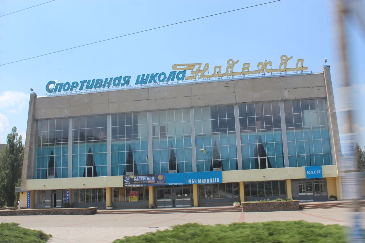 Літній фасад спортивного комплексу «Надія» з великою назвою спортивної школи над входом.