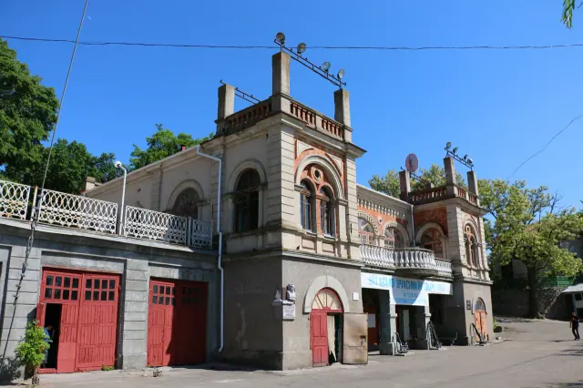 Архівний вигляд історичної будівлі Миколаївського яхт-клубу з червоно-сірим фасадом, арковими вікнами та центральним входом.